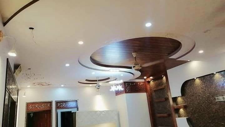 Finished modern curved false ceiling site execution with cove lighting and wooden accent